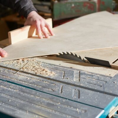 Stolarz przycina sklejkę na wymiar na pile tarczowej.